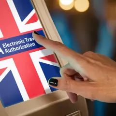 Palec dotyka ekranu z flagą Wielkiej Brytanii i napisem ETA. Czy Anglia jest w Schengen? Nie, wymaga ETA.