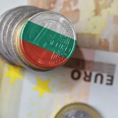 Monety z flagą Bułgarii na tle eurobanknotów. Waluta Bułgaria w kontekście europejskim.