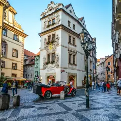 Uliczka w Pradze z zabytkowym czerwonym kabrioletem i pięknymi kamienicami. To urokliwa złota uliczka Praga, pełna historii.