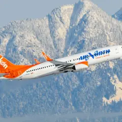 Boeing 737-900 linii Air North z charakterystycznym ogonem w barwach Yukon wzbija się na tle ośnieżonych gór.