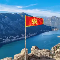 Czarnogóra, z flagą na tle gór i zatoki, nie jest w UE.