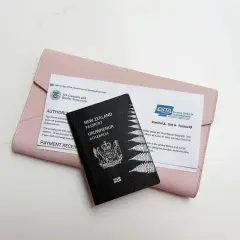Paszport Nowej Zelandii i dokument ESTA na różowej kosmetyczce. Ta scena zapowiada podróż.