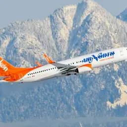 Boeing 737-900 linii Air North z charakterystycznym ogonem w barwach Yukon wzbija się na tle ośnieżonych gór.