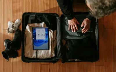 Pakowanie bagażu podręcznego: ubrania, buty i tablet do walizki.
