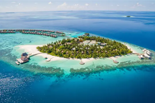 Rajskie Malediwy wiza: tropikalna wyspa z luksusowymi bungalowami na wodzie i białymi plażami, otoczona turkusową wodą.