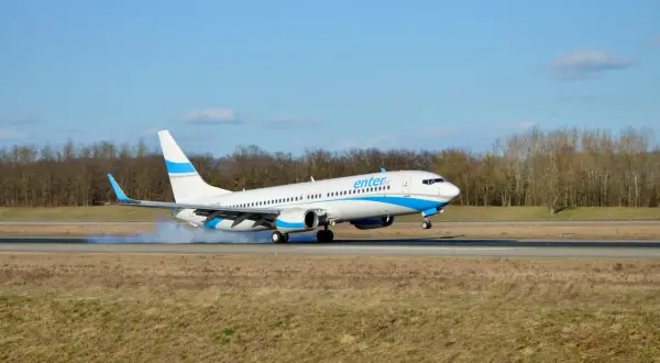 Samolot Enter Air ląduje na pasie startowym, unosząc kurz.