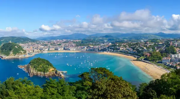 Widok na zatokę La Concha w San Sebastián. Widać miasto, plażę, góry i liczne łodzie na wodzie. Idealne miejsce na loty widokowe.