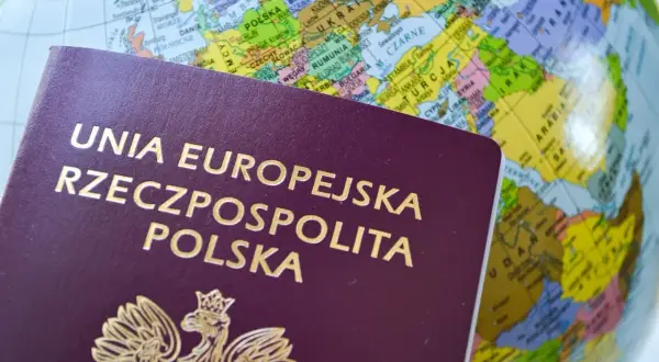 Polski paszport na tle globusa z zaznaczoną Europą.