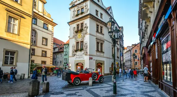 Uliczka w Pradze z zabytkowym czerwonym kabrioletem i pięknymi kamienicami. To urokliwa złota uliczka Praga, pełna historii.