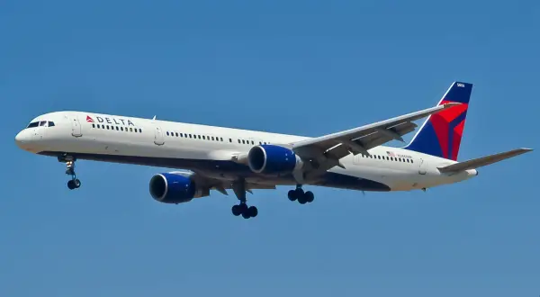 Boeing 757-300 linii Delta z wysuniętym podwoziem zbliża się do lądowania na tle błękitnego nieba.