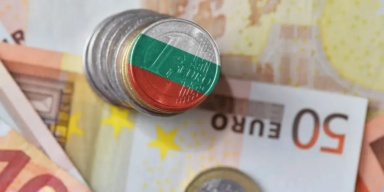 Monety z flagą Bułgarii na stosie, obok banknotów euro. Waluta Bułgarii w kontekście europejskim.
