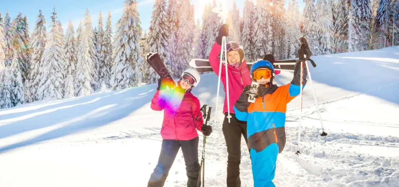 Rodzina na stoku, idealne miejsce, gdzie na ferie z dziećmi. Radosne dzieci z nartami i snowboardem cieszą się zimą.