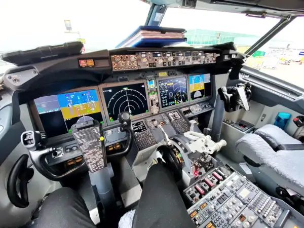Kokpit samolotu Boeing 737 z widokiem na panele sterowania, ekrany nawigacyjne i yoke.