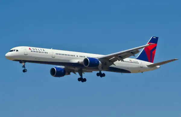 Boeing 757-300 linii Delta z wysuniętym podwoziem zbliża się do lądowania na tle błękitnego nieba.
