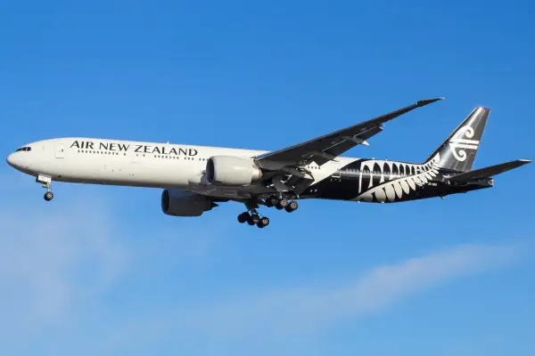 Boeing 777 Air New Zealand z charakterystycznym czarnym malowaniem na ogonie, w locie na tle błękitnego nieba.